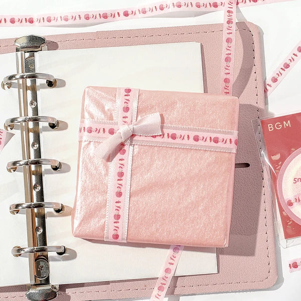 Pink planner with decorative ribbon and card on a white background
