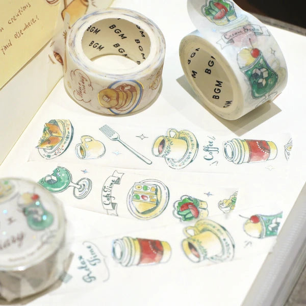 Decorative washi tape with illustrations of coffee cups, cakes, and other items on a white surface.