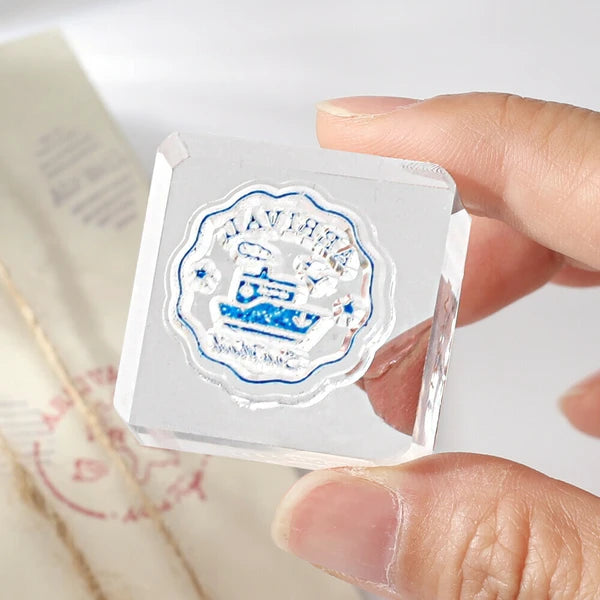 Clear crystal cube with a logo held by a hand on a light background