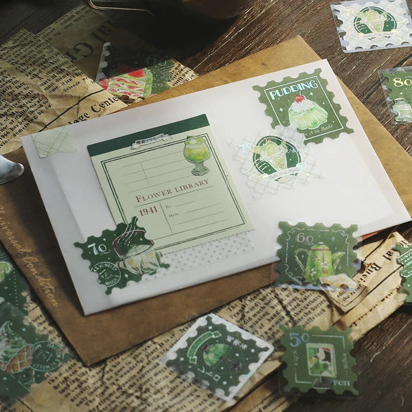 Book with green and white design on a wooden surface with vintage-style stamps.