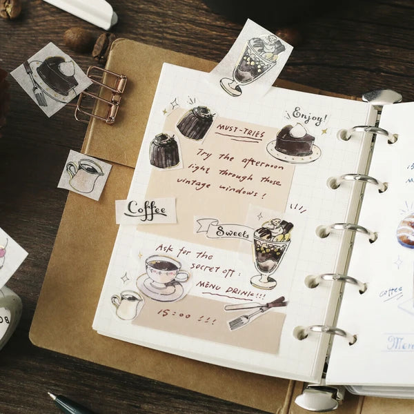 Notebook with coffee-themed stickers and illustrations on a wooden surface